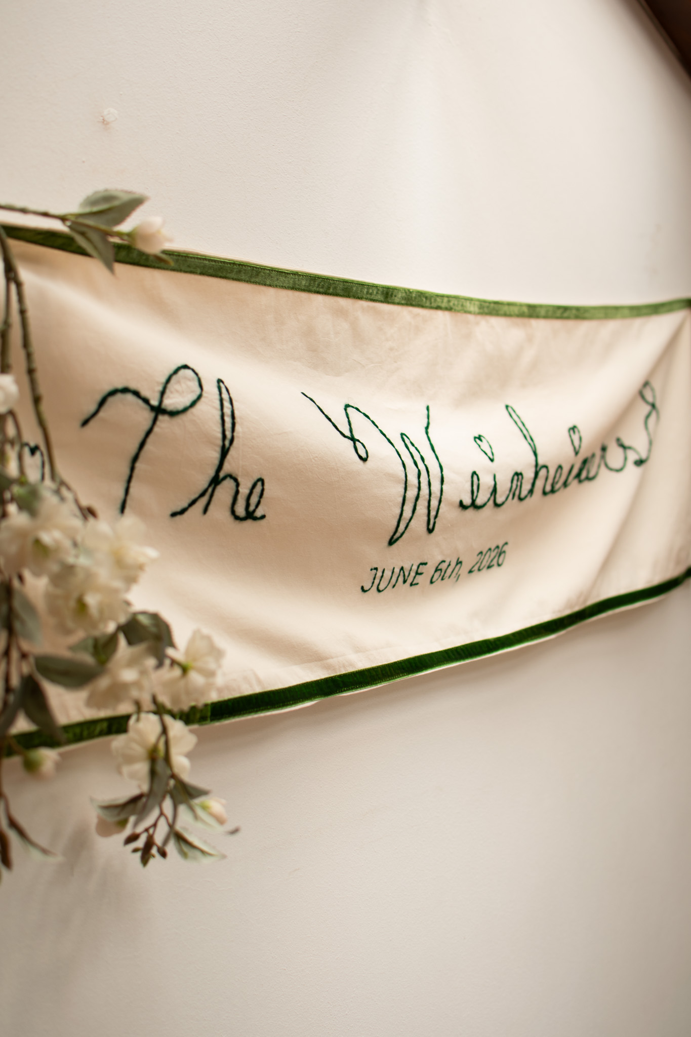 Embroidered wedding banner with floral details hanging on wooden arch